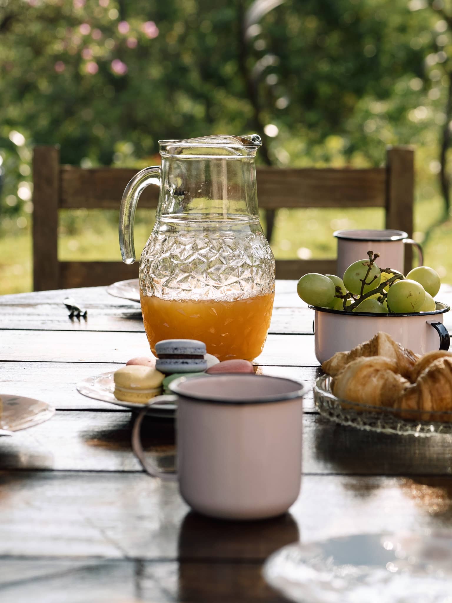 Jarra de suco, frutas e canecas esmaltadas na mesa do café colonial