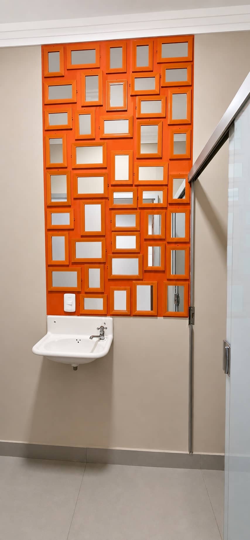 Parede de cobogó laranja iluminada no lavabo