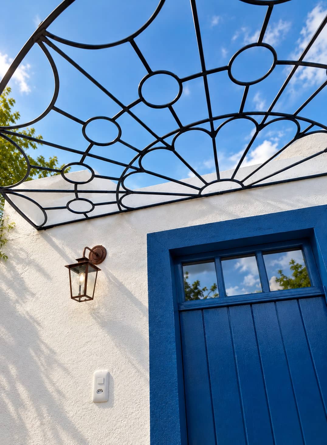Gradil de ferro em arco contra o céu azul, acima da porta azul