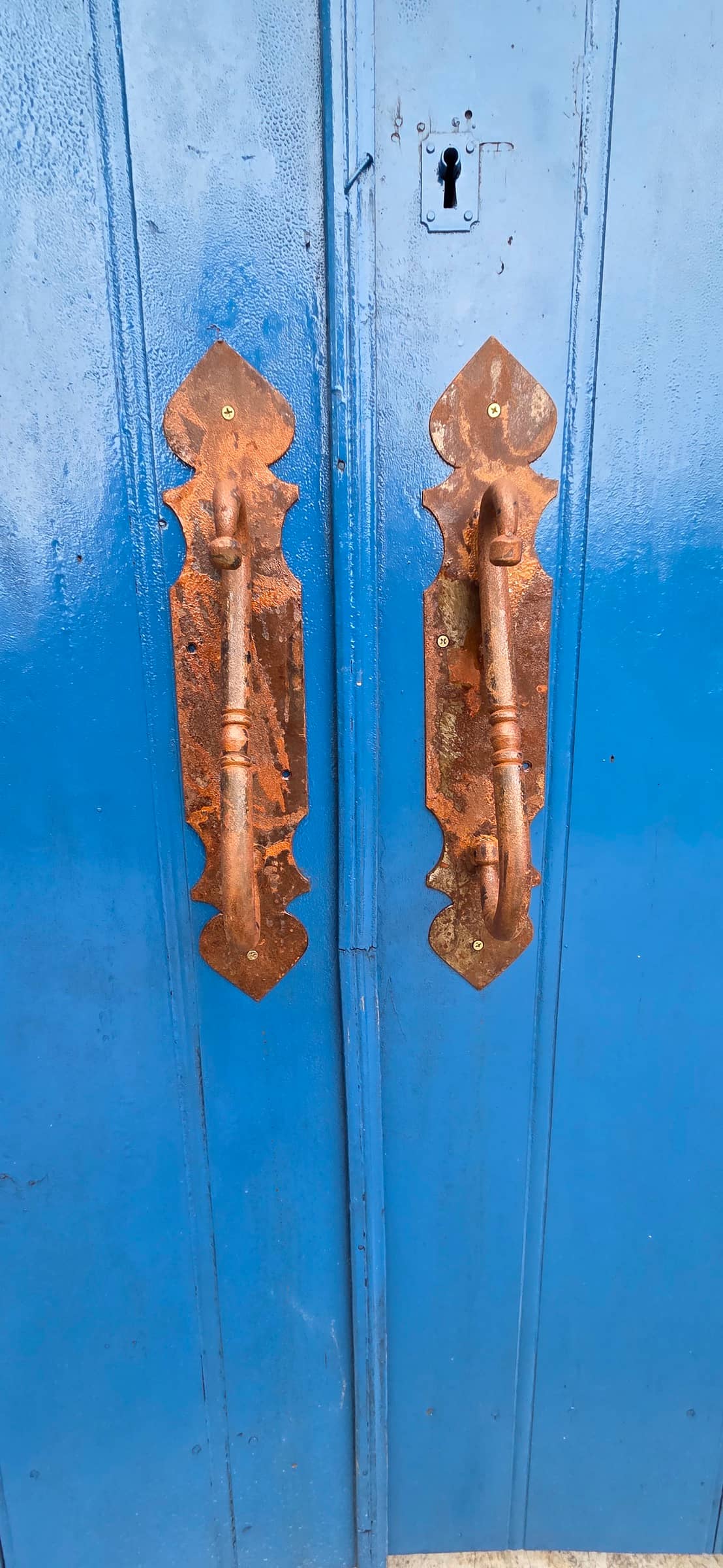 Maçanetas de cobre em uma porta de madeira azul