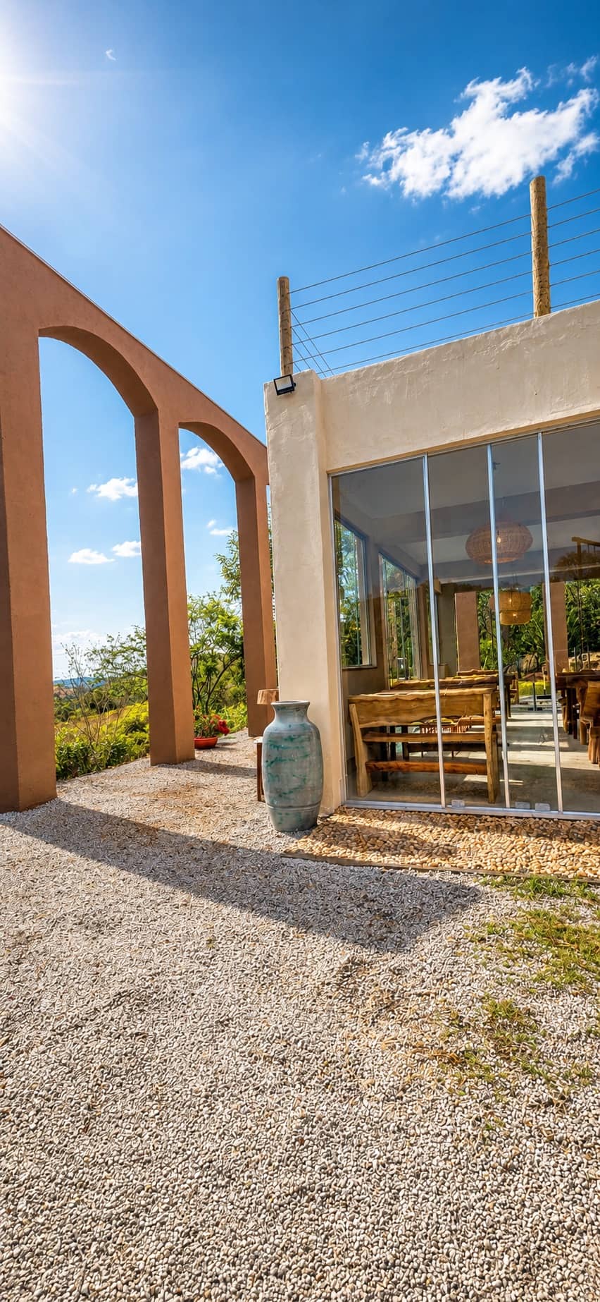 Arcos externos e salão envidraçado com vista para a mata
