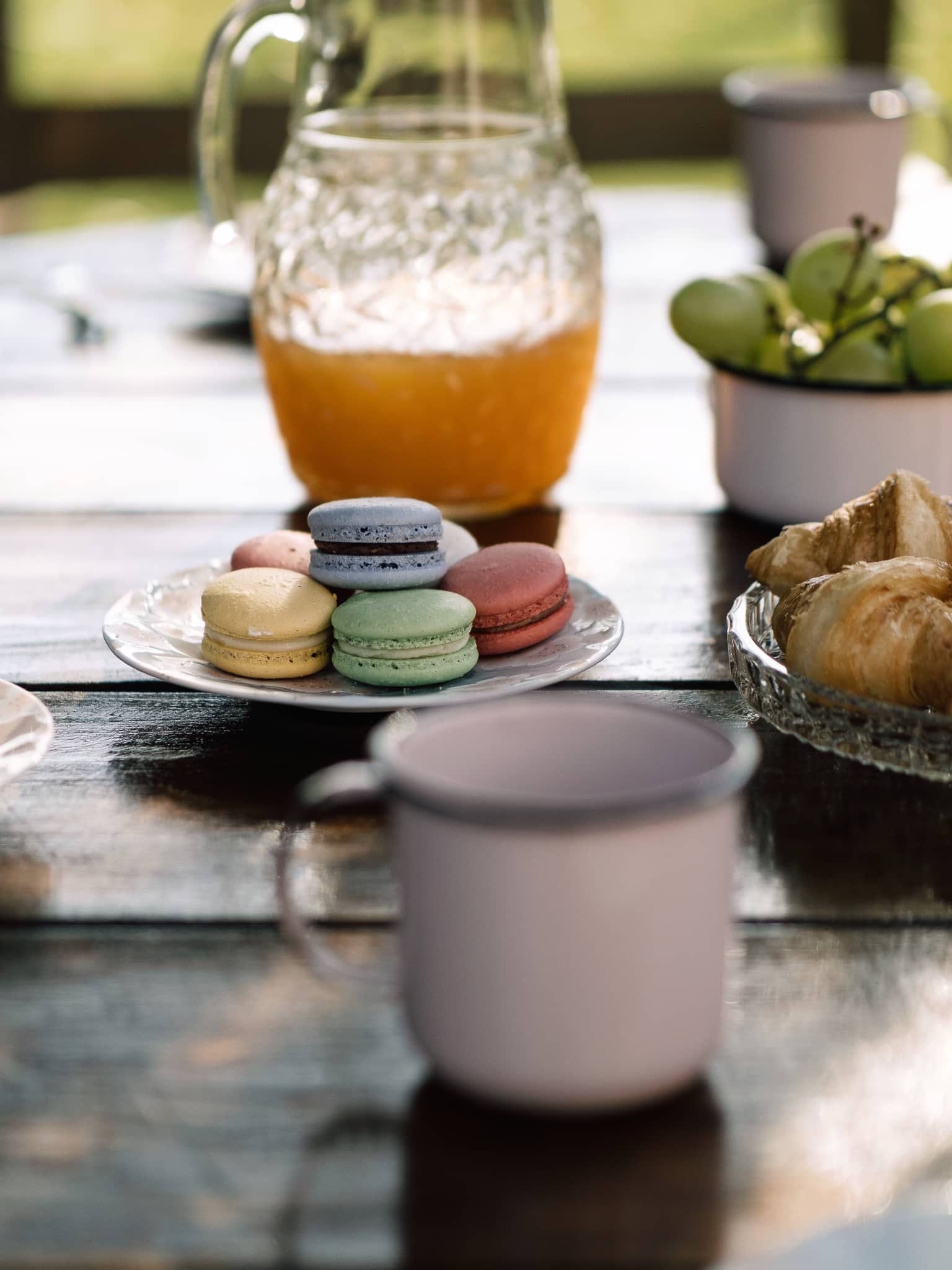Café colonial com jarra de suco, macarons e canecas esmaltadas