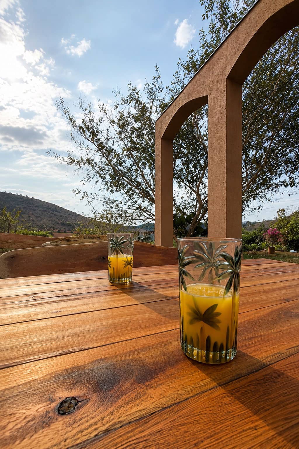 Drinks sobre mesa de madeira sob um arco, com as montanhas do Vale do Aço ao fundo