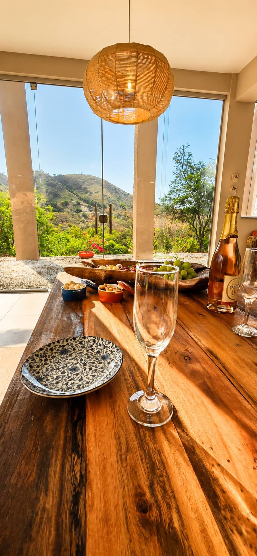 Mesa de madeira maciça com taças e petiscos diante da janela com vista para as montanhas