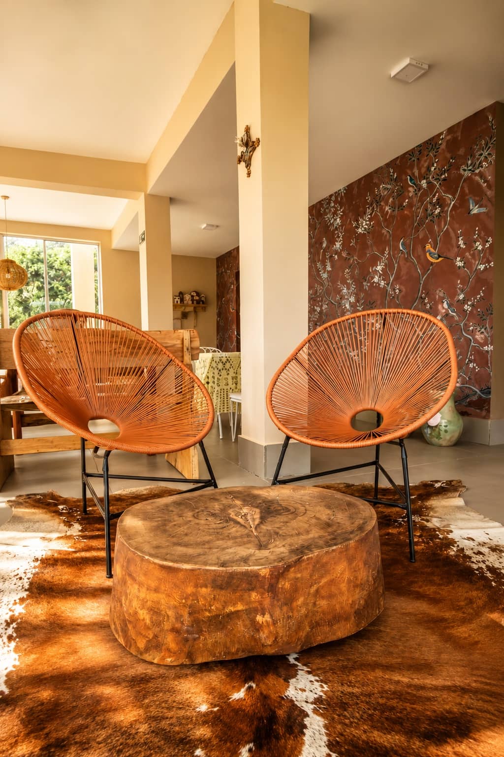Sala de estar com poltronas de corda, mesa de tronco e tapete de couro
